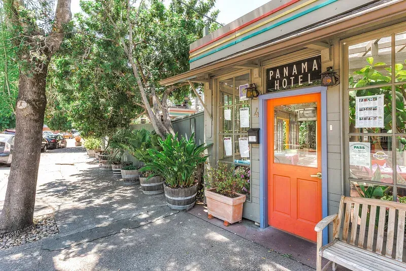The hotel's orange front door, framed by potted plants